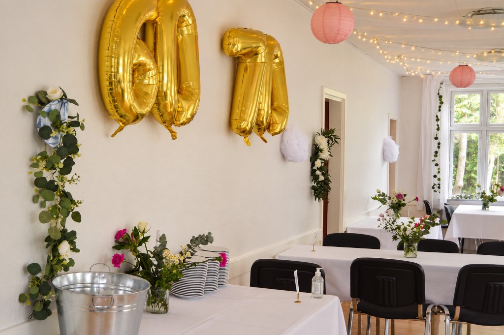 Guldballoner med 60 og 70, blomster og lyskæder i lokalet